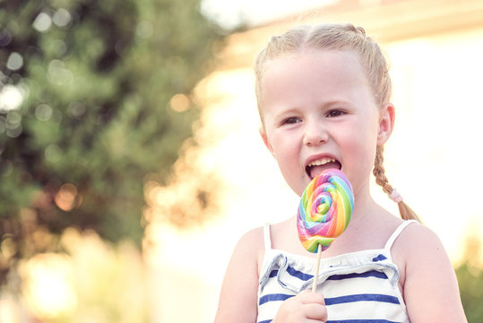 Beautiful blonde girl-tasting colored lollipop