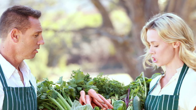 Smiling farmer couple holding a vegetable basket