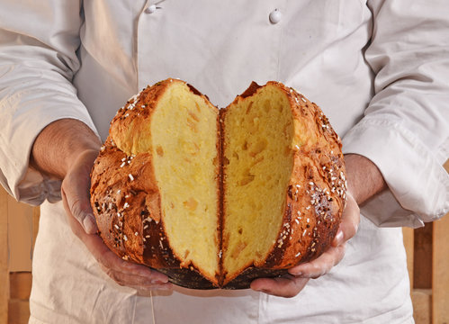 Manos de un panadero sujetando un panettone cortado a mitad.