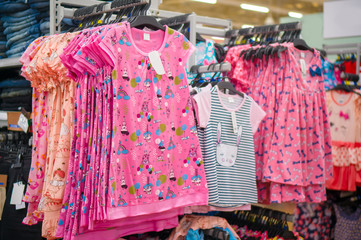 Small pink girl dresses with different patterns on hangers in st