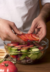 Man puts all the ingredients in a salad close up