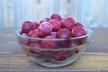 Frozen cherries in a glass bowl on wooden  background