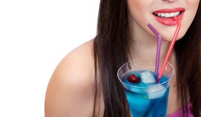 Close-up of a young woman drinking blue cocktail with ice and cherry