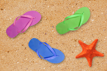 Fototapeta na wymiar colorful beach shoes and starfish over yellow sand background