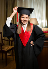 girl in graduation cap and gown posing at classic interior