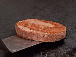 Cocinando carne de hamburguesa sobre una plancha caliente.