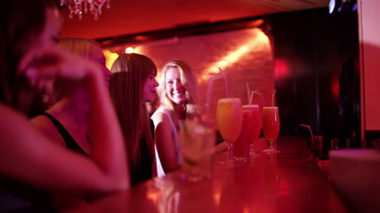 Girls toasting each other at a bar with cocktails