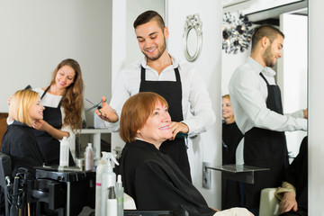 Obraz na płótnie Canvas Elderly woman cuts hair at the hair salon
