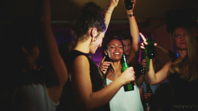 Young African American woman dancing happily in a night club with friends