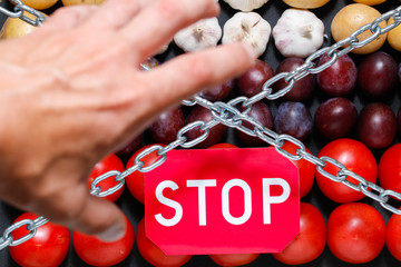 Chain, a 'stop' sign and a grabbing hand on a vegetables background, in context of sanctions and...