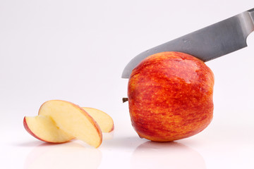 Cool fresh red apple sliced with kitchen knife isolated on white