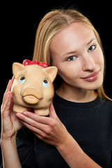 Junge Frau h&auml;lt ein Sparschwein in der Hand