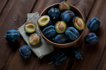 Ripe plums over dark brown wooden surface, high angle view