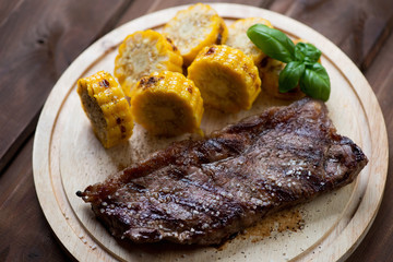 Grilled striploin beefsteak and corncob slices, close-up