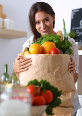 Young woman holding grocery shopping bag with vegetables and