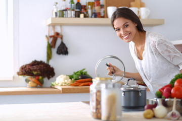 Young woman standing by the stove in the kitchen
