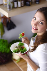 Young woman eating salad and holding a mixed salad 