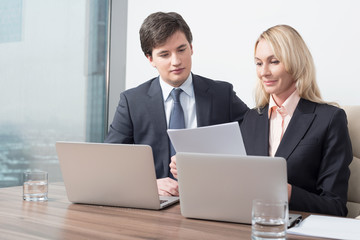 Business couple is double checking some essential business information. Panoramic office.