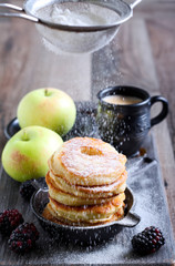Dusting with icing sugar over apple fritters