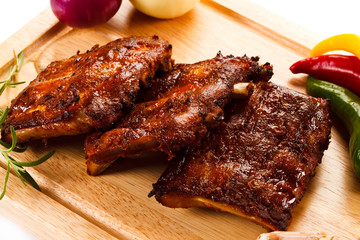 Barbecued ribs with vegetables on cutting board 