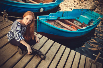 Obraz premium Beautiful sexy woman is dressed in a sea stripped vest sits on the seashore dreams.