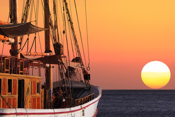 Forward! To dream! / Sailing ship floating by sea on a sunset background