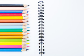 notebook with color pencils on background