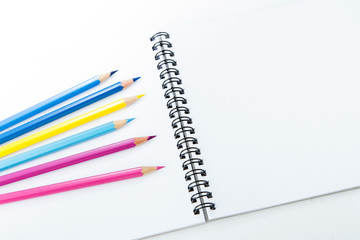 notebook with color pencils on background