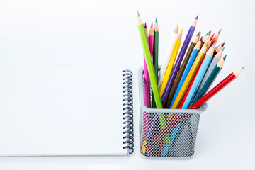 notebook with color pencils on background