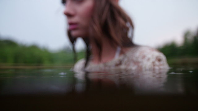Hippie girl gazing at you while in a natural lake