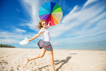 Cheerful young girl with rainbow umbrella having fun on the