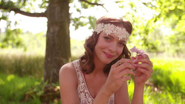 Smiling hippie girl in a park holding wild flower