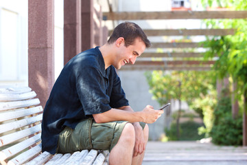 Smiling man reading text message on cell phone
