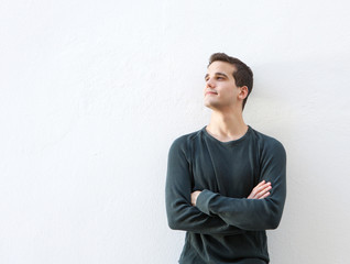 Young man standing against white background with arms folded