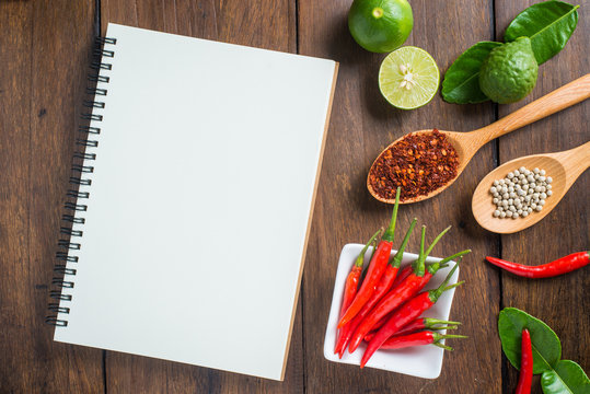 Recipe notebook, rice, Red chilli, garlic and lemon on wooden ba