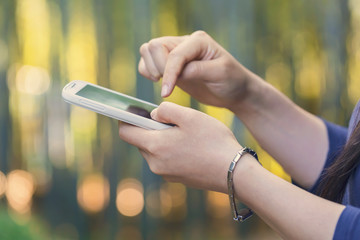 Woman using her phone in the forest at sunset