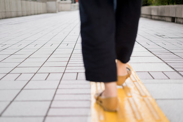 歩道の誘導ブロックを歩く女性