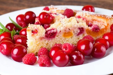 Detail view on slice of fruit pie with berries around