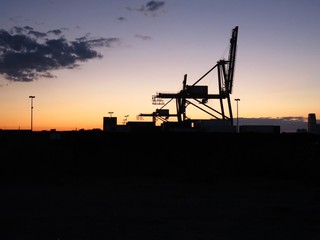 Industrial landscape: silhouette of gantry cranes on Brooklyn waterfront shipping docks at sunset