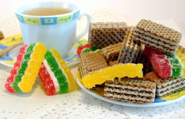 Cup of tea, wafers, jelly on a plate on a light background