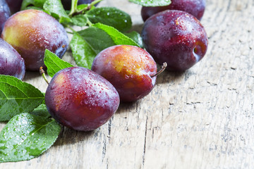 Delicious blue-orange plums with drops of water on the old woode