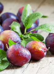 Delicious blue-orange plums with drops of water on the old woode