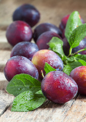 Delicious blue-orange plums with drops of water on the old woode