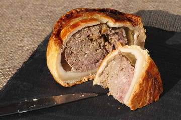 Pork pie sliced slate.
Slice of pork pie on a slate surface.