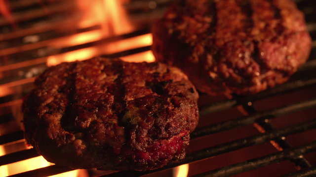 Beef burger patties cooking on the grill of a barbecue