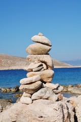 A pile of stones on ftenagia beach at Emborio on the Greek island of Halki. The uninhabited island of Nissos is in the background.
