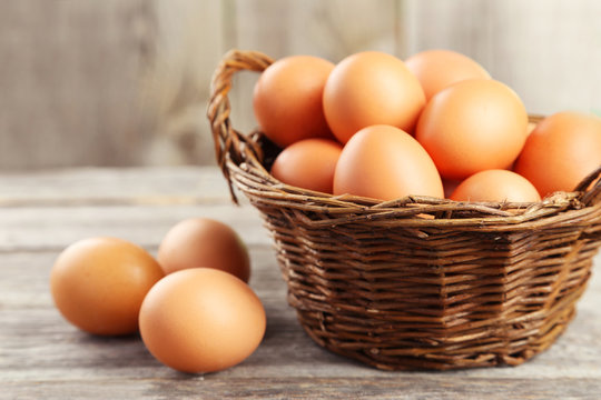 Chicken eggs in basket on grey wooden background