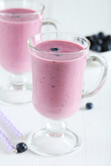 Fresh blueberry smoothie in the glasses on white wooden backgrou
