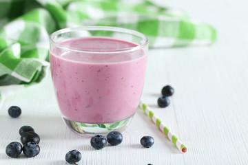 Fresh blueberry smoothie in the glass on white wooden background