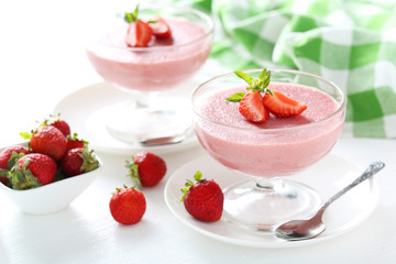 Tasty strawberry mousse in glass on white wooden table